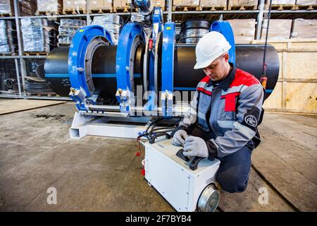 Stepnogorsk, Kazakhstan - April 04, 2012: Plastic pipes production plant. Engineer adjusting pipes joining equipment. Stock Photo