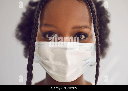 Headshot of beautiful young black woman wearing medical face mask looking at camera Stock Photo