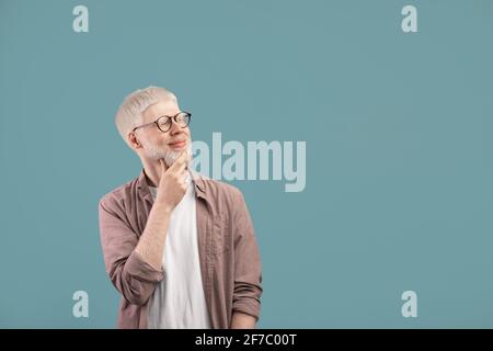 Pensive albino guy thinking over decision, looking at empty space over turquoise studio background Stock Photo
