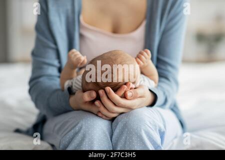 Mother Care. Unrecognizable mom holding newborn baby on her laps Stock Photo