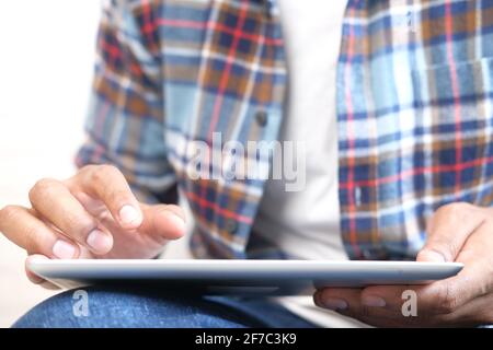 Work from home concept, young man working on digital tablet sitting on floor  Stock Photo