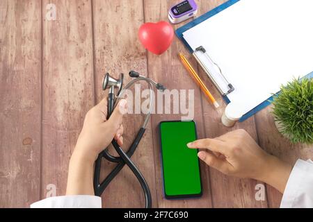 top view of female doctor using smart phone on clinic desk Stock Photo