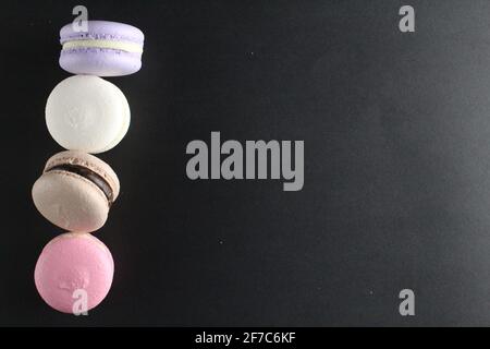 Four macaroons view from above on a black background with a place for ...