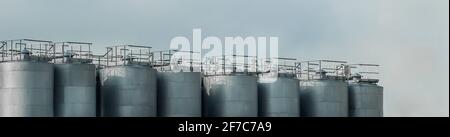 Industrial tanks for storing, receiving and preparing liquid products against a blue sky. Stock Photo