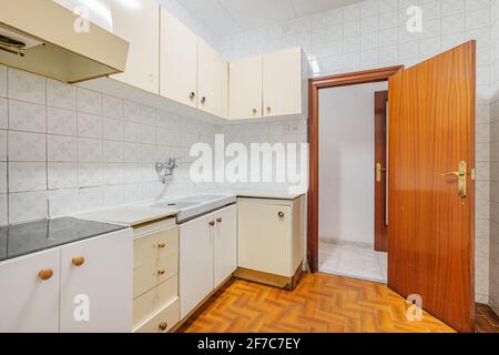 Bright empty kitchen with tiled floor and walls before renovation. Old typical apartment in Barcelona for rent or sale. Stock Photo