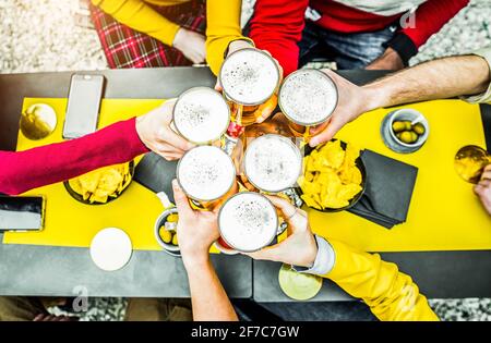 Group of people toasting a beer in brewery pub - Friends having fun drinking alcohol at bar restaurant - People, food and drink concept Stock Photo