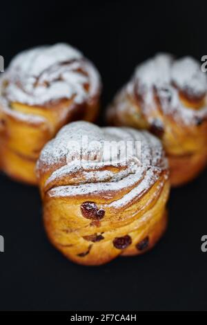 Fresh Easter pie or bakery concept. Cute cruffins with raisins and white sugar powder on it on black background. Vertical image. High quality photo Stock Photo