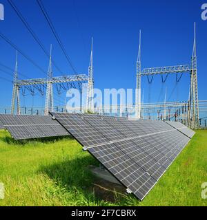 Solar energy panels in the background high voltage power substation. Stock Photo