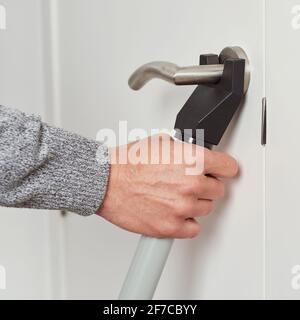 a young caucasian man secures the door of his house with a door blocker security bar Stock Photo