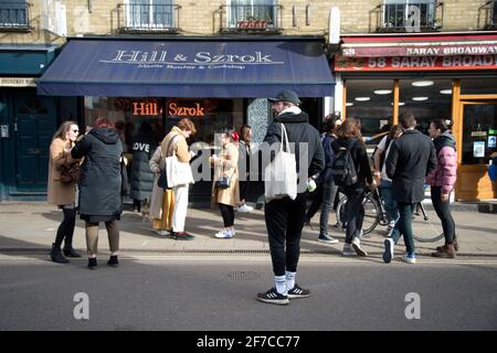 London, England, UK. Hackney. London Fields. Broadway Market. Young people on the street in front of Hill and Szrok butchers. Stock Photo