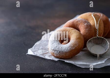 Sweet donuts with powder sugar on black background. Food concept. Copy space. Stock Photo