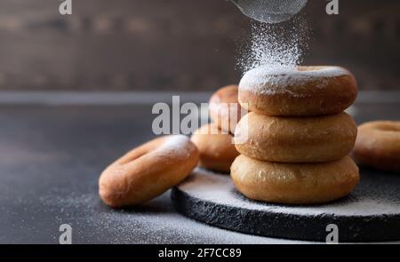 Sweet donuts with powder sugar on black background. Food concept. Copy space. Stock Photo