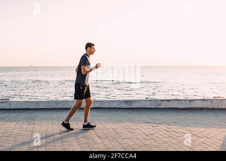 Young man jogging at the seafront early at the morning. Stock Photo