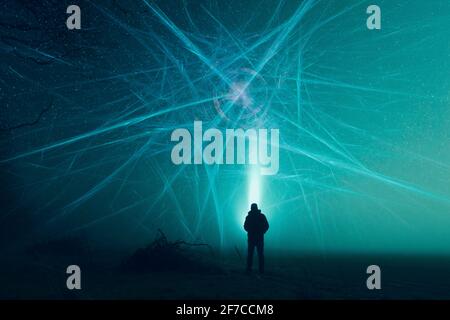 A science fiction concept. Of a man with a torch looking at an alien structure in the sky, in a field on a misty winters night. Stock Photo