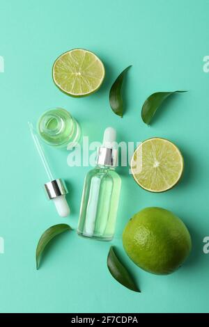 Dropper bottles with oil and limes on mint background Stock Photo