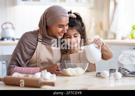 Cute Little Arab Girl Baking Together With Her Islamic Mom In Kitchen Stock Photo