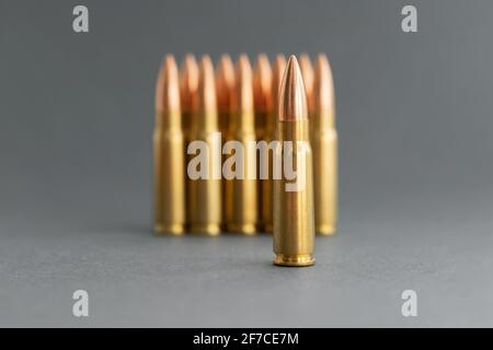 Bullets on gray background. Cartridges 7.62 caliber for Kalashnikov assault rifle closeup. Selective focus on foreground. Stock Photo