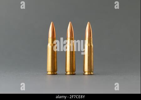 Three bullets on gray background. Cartridges 7.62 caliber for Kalashnikov assault rifle closeup. Stock Photo