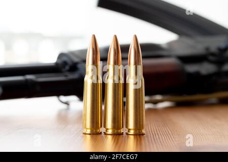 Three bullets against blurred Kalashnikov assault rifle background. Cartridges 7.62 caliber for ak 47 closeup