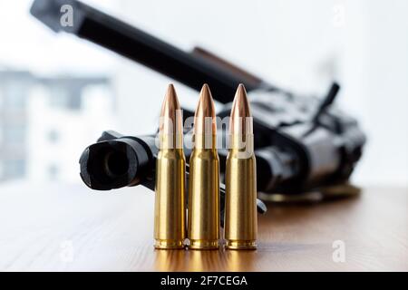 Three bullets against blurred Kalashnikov assault rifle background. Cartridges 7.62 caliber for ak 47 closeup.