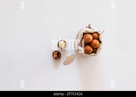 Raw macadamia nuts in canvas bowl on a white solid background. Minimal flat composition Stock Photo