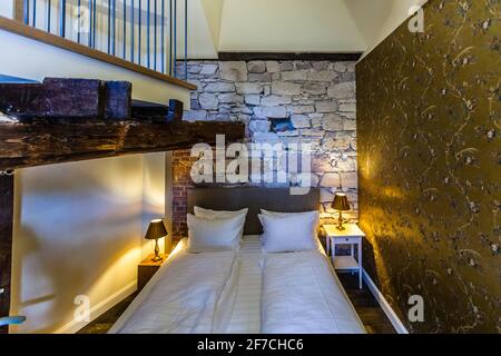 Small, but fine maisonette suite with everything the Renthof has to offer: noble wallpaper, old beams, roher stone, and a view of the old brothers church from the bathroom Stock Photo