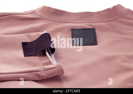 mock up fabric blank black patch for the brand logo on the arm and black eco leather tag on the beige sweater Stock Photo