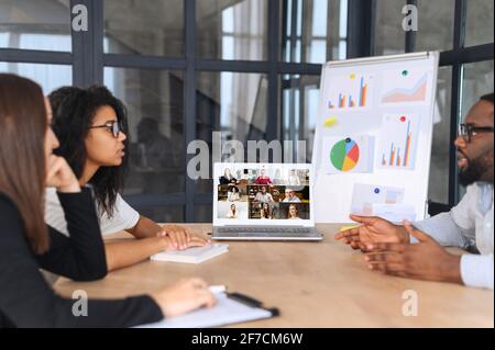 Multi ethnic group of business people having discussion with another colleague via video call in office, need everyone to give the best ideas, putting plans into motion, finding solutions together Stock Photo
