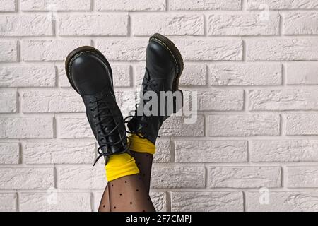 Woman's feet in black leather boots with polka dot tights and yellow socks Stock Photo