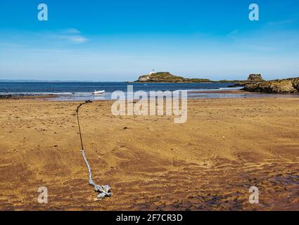 Rubber dinghy anchored on empty beach shoreline on sunny day with view of Fidra Island, Firth of Forth, Scotland, UK Stock Photo