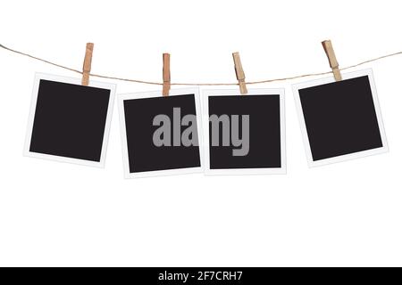 Four blank instant photo frames hanging on a rope, isolated on white background Stock Photo
