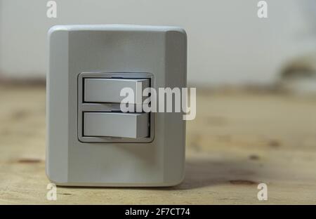 Double switch electrical switch on wooden background. Electric material. Utensil for installation of electrical network. Wall plug. Residential lamp s Stock Photo