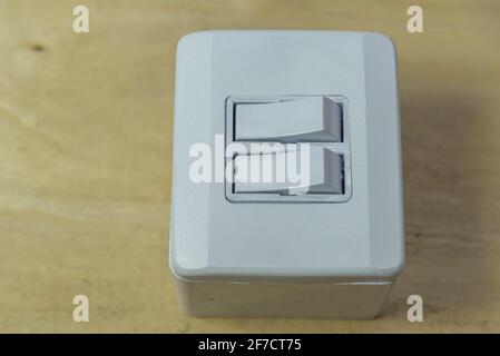 Double switch electrical switch on wooden background. Electric material. Utensil for installation of electrical network. Wall plug. Residential lamp s Stock Photo