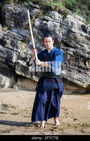 Young man practicing Kendo with wooden sword. Word Kendo can be translated as 'the way of the sword'. Stock Photo