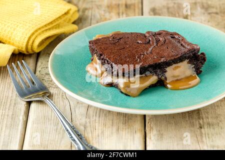 A freshly made salted caramel brownie. Still warm from the oven the caramel is melting and oozing onto the plate Stock Photo