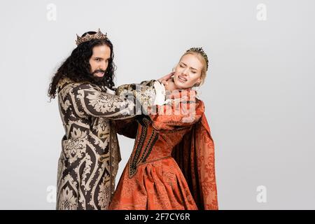 hispanic king in medieval clothing choking scared queen in crown isolated on white Stock Photo