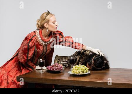 blonde queen pulling poisoned hispanic king in medieval clothing isolated on white Stock Photo