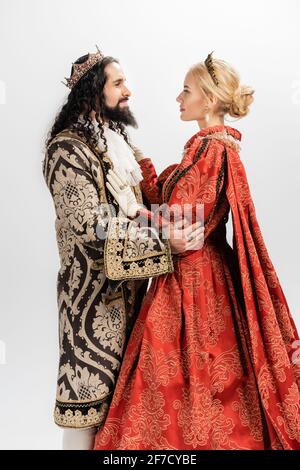 interracial king and queen in medieval clothing and crowns hugging isolated on white Stock Photo