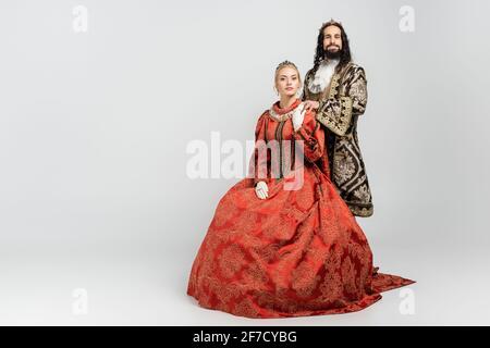 interracial king and queen in medieval clothing and crowns looking at camera on white Stock Photo