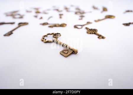 Close up of a vintage key with a heart engraving and collection of other scattered keys in the background. Love symbol. Valentine’s day concept. Stock Photo