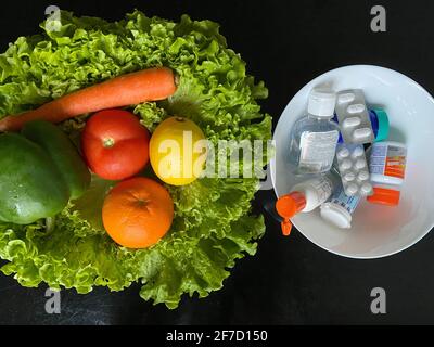 Fresh natural vegetables vs pills. Natural vitamin in fruits vs synthetic vitamin in pills. Choice between natural and synthetic way of health care. Stock Photo