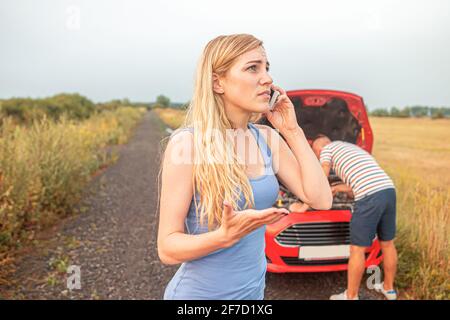 A broken car. A young couple is trying to call for help in a car breakdown. Stock Photo