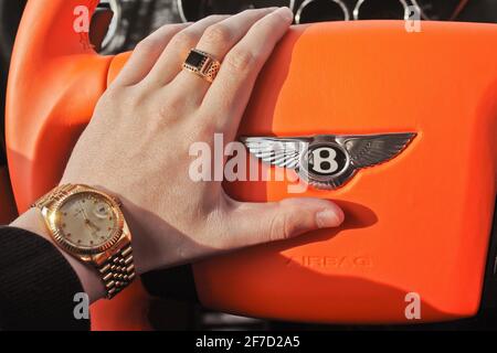 Kiev, Ukraine - April 9, 2014: Bentley Continental GT Mansory. A man holds the steering wheel of a luxury car. Gold watch and a ring Stock Photo