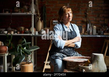 Charming elderly woman working in pottery workshop Stock Photo