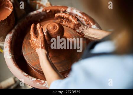 Old woman hands sculpting clay pot on pottery wheel Stock Photo