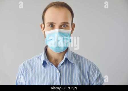 Portrait of happy friendly office worker in blue medical face mask looking at camera Stock Photo