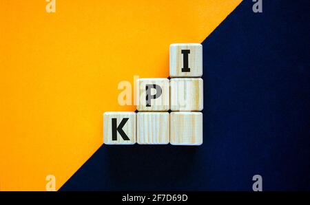 KPI, key performance indicator symbol. Wood cubes with words 'KPI, key performance indicator' on orange background, copy space. Businessman hand. Busi Stock Photo