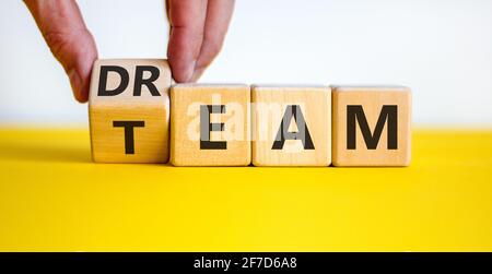 Dream team symbol. Businessman turns the cube and changes the word 'dream' to 'team'. Beautiful yellow table, white background. Business and dream tea Stock Photo