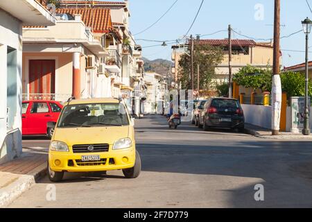 Zakynthos, Greece - August 14, 2016: Street view with parked cars on a summer sunny day. People walk the street Stock Photo