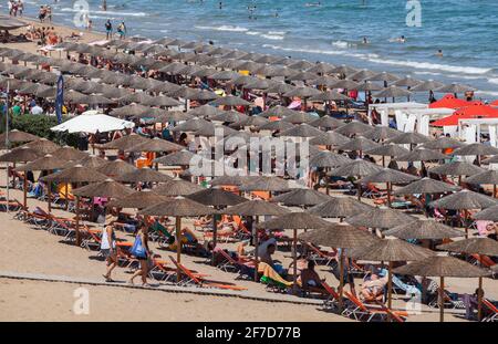 Zakynthos, Greece - August 15, 2016: Tourists rest under strw umbrellas on Banana Beach of Zakynthos on a sunny summer day Stock Photo